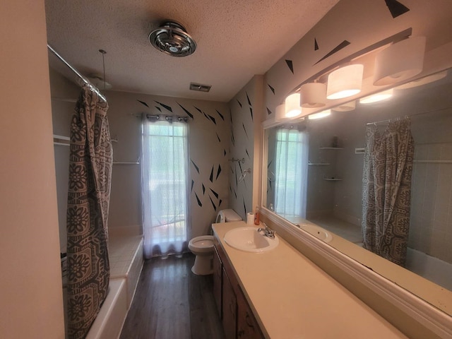 full bathroom with hardwood / wood-style flooring, a textured ceiling, vanity, shower / bath combo, and toilet