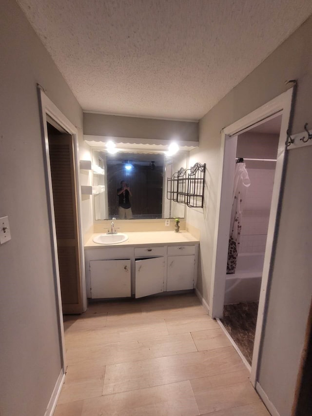 bathroom featuring a textured ceiling, hardwood / wood-style flooring, vanity, and shower / bath combo