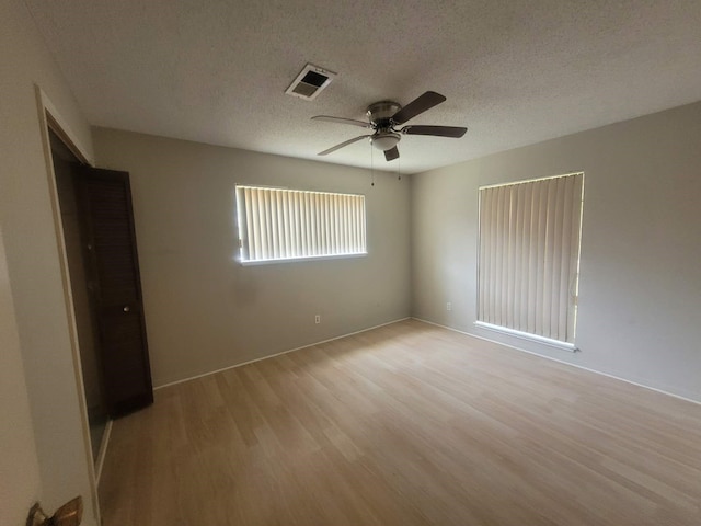 empty room with a textured ceiling, light hardwood / wood-style flooring, and ceiling fan