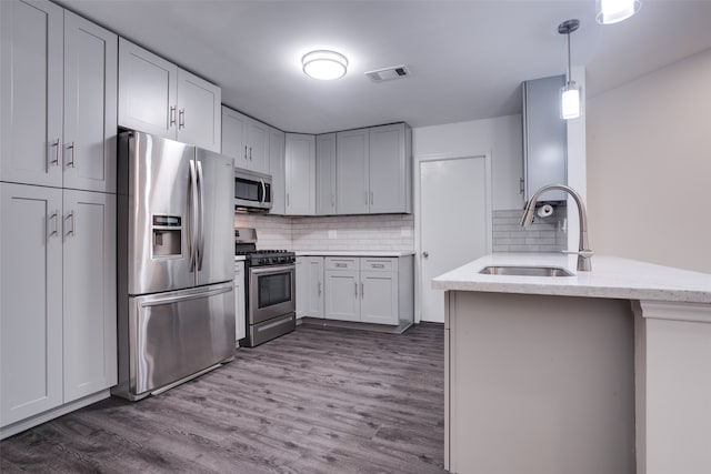 kitchen featuring kitchen peninsula, sink, appliances with stainless steel finishes, and dark wood-type flooring