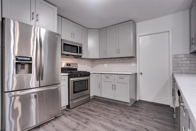 kitchen featuring decorative backsplash, stainless steel appliances, and light hardwood / wood-style floors