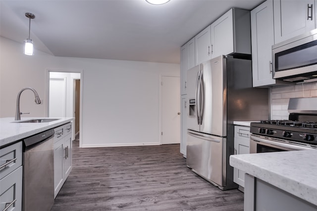 kitchen with dark wood-type flooring, sink, tasteful backsplash, decorative light fixtures, and stainless steel appliances