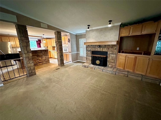 living room featuring lofted ceiling, light carpet, a stone fireplace, crown molding, and ornate columns