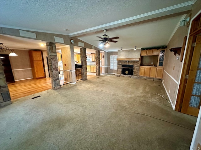 unfurnished living room with a textured ceiling, lofted ceiling, a fireplace, ceiling fan, and ornate columns