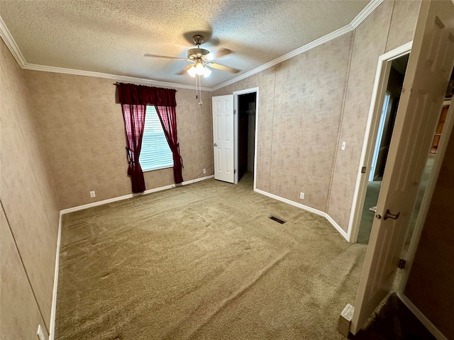 unfurnished bedroom with a textured ceiling, ornamental molding, ceiling fan, and carpet floors