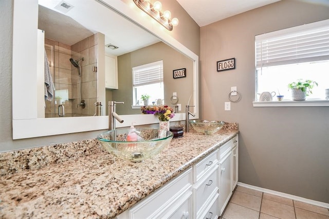 bathroom featuring a shower with shower door, dual vanity, and tile patterned flooring