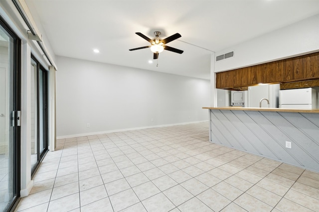 interior space featuring light tile patterned flooring, white fridge, sink, and ceiling fan