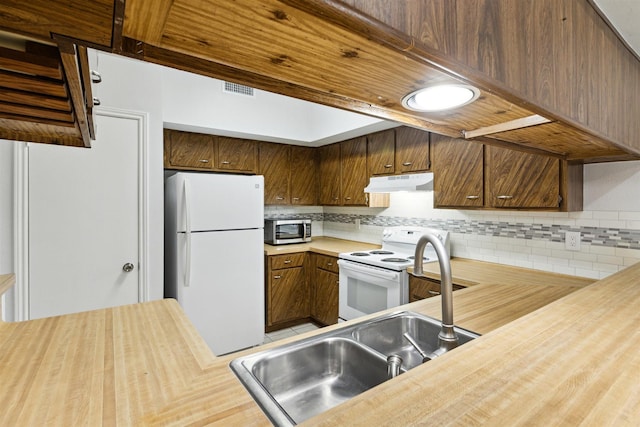 kitchen with sink, decorative backsplash, white appliances, and kitchen peninsula