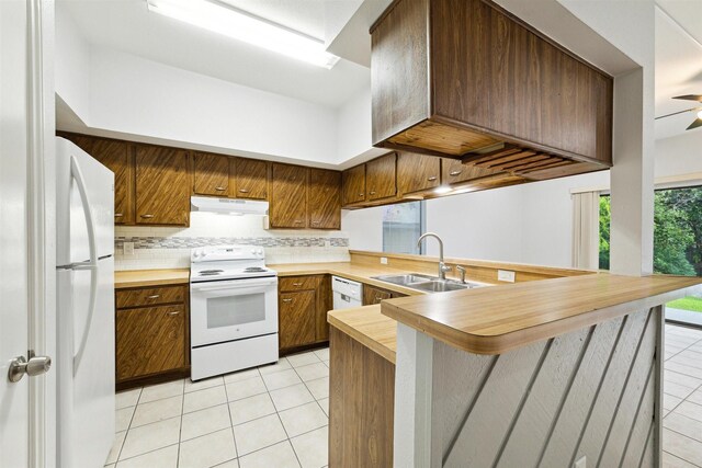 kitchen featuring kitchen peninsula, decorative backsplash, white appliances, sink, and light tile patterned floors