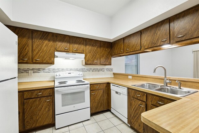 kitchen with light tile patterned floors, decorative backsplash, white appliances, sink, and kitchen peninsula