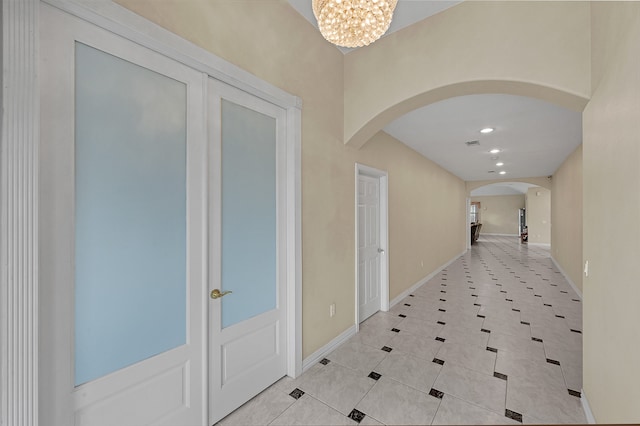 corridor featuring a notable chandelier, light tile patterned floors, and french doors