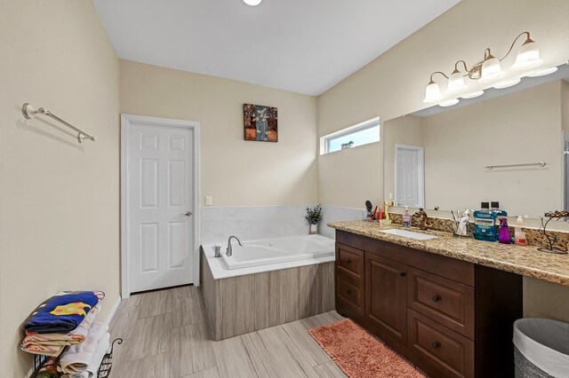 bathroom with tiled tub, vanity, and tile patterned floors