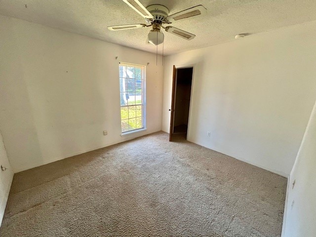 carpeted spare room featuring a textured ceiling and ceiling fan