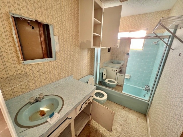 full bathroom featuring vanity, a textured ceiling, tiled shower / bath combo, and toilet