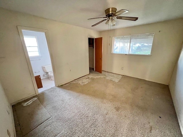 unfurnished bedroom featuring ensuite bathroom, ceiling fan, and light colored carpet