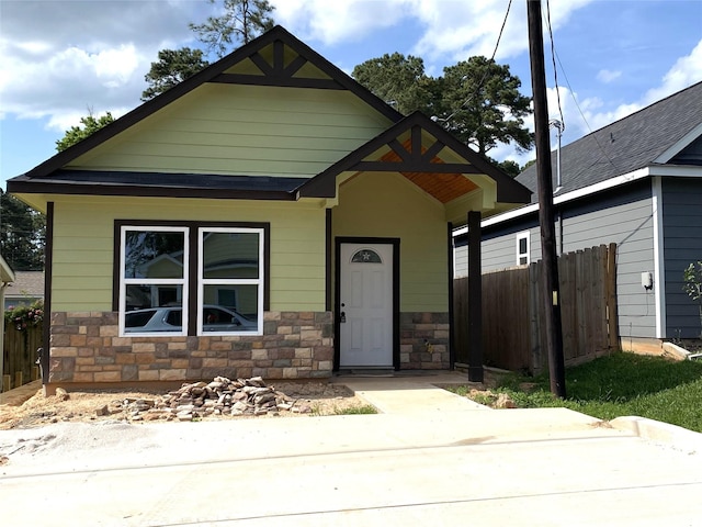 view of front of property with a patio, fence, and stone siding