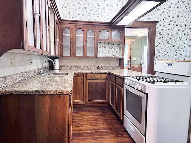 kitchen with light stone counters, dark hardwood / wood-style floors, sink, and white range with gas stovetop