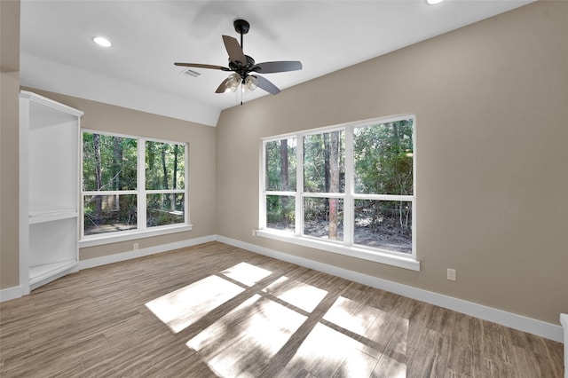 empty room with ceiling fan, vaulted ceiling, and light hardwood / wood-style flooring