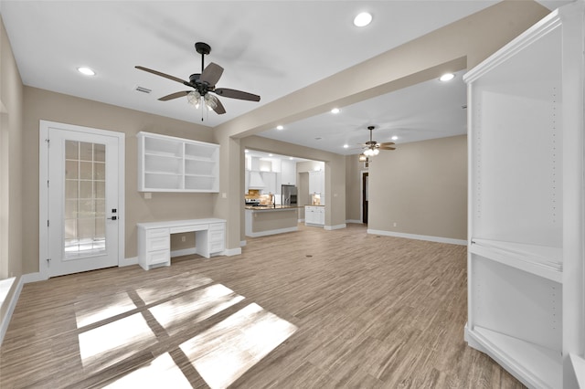 unfurnished living room featuring ceiling fan and light wood-type flooring