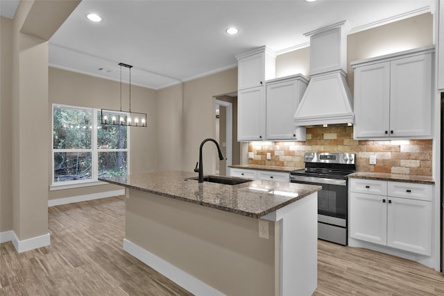 kitchen featuring stainless steel electric stove, sink, white cabinetry, an island with sink, and dark stone counters