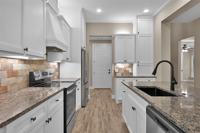 kitchen with white cabinets, dark stone counters, appliances with stainless steel finishes, ceiling fan, and sink