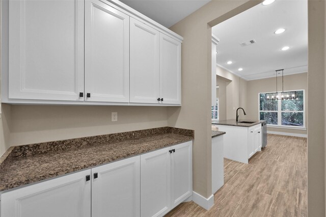 kitchen with sink, white cabinets, dark stone countertops, and pendant lighting