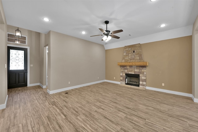 unfurnished living room featuring ceiling fan, light hardwood / wood-style floors, and a stone fireplace