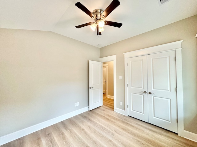 unfurnished bedroom featuring lofted ceiling, light hardwood / wood-style flooring, ceiling fan, and a closet