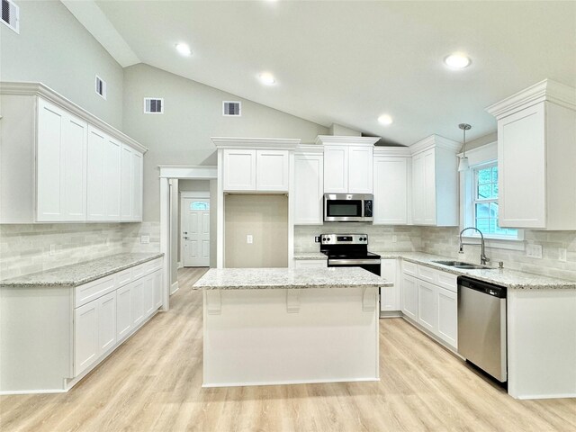 kitchen with white cabinets, light stone countertops, stainless steel appliances, and sink