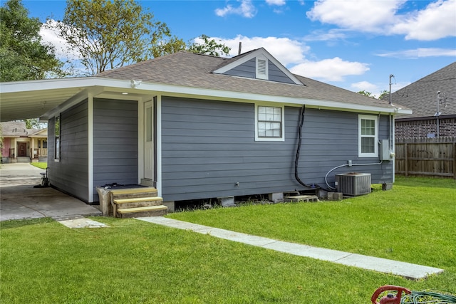 rear view of house with central AC and a yard