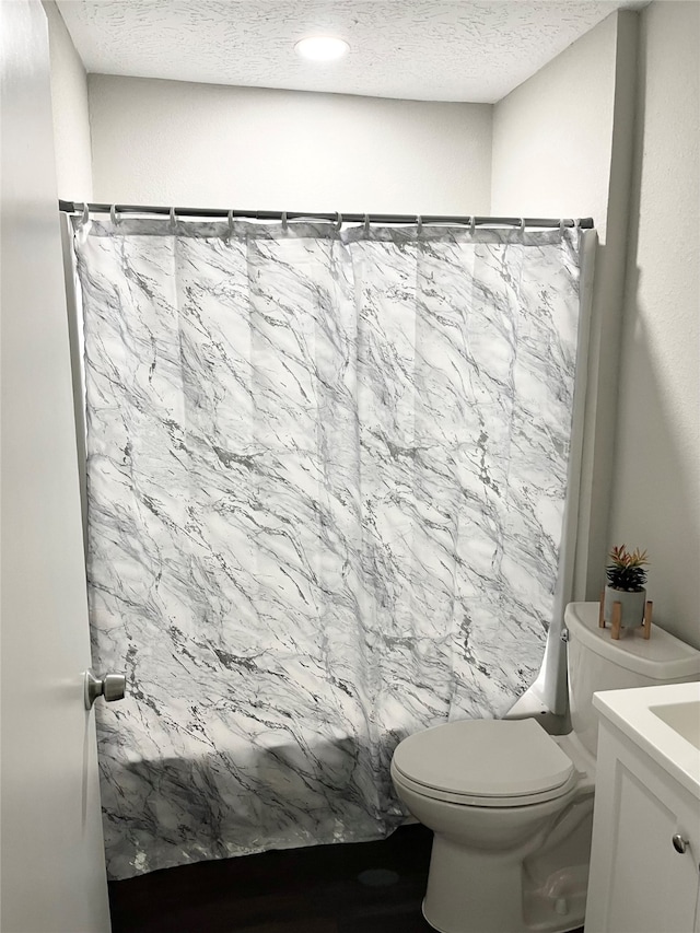 bathroom featuring vanity, toilet, curtained shower, and a textured ceiling