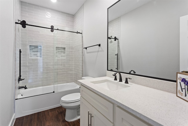 full bathroom with vanity, hardwood / wood-style flooring, shower / bath combination with glass door, and toilet