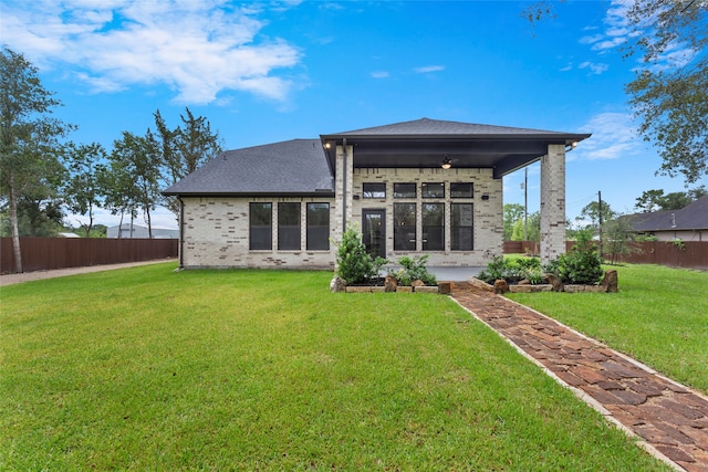 rear view of house featuring a yard and ceiling fan