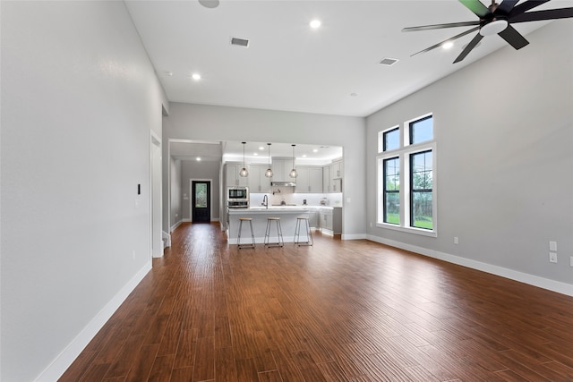 unfurnished living room with ceiling fan, sink, and hardwood / wood-style flooring