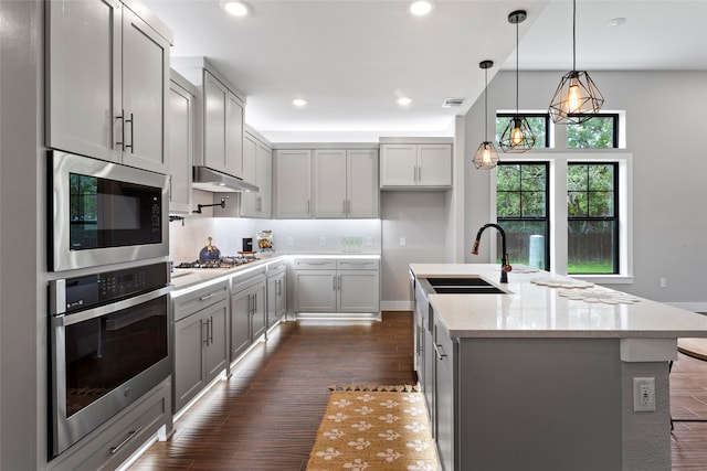 kitchen featuring dark hardwood / wood-style flooring, sink, light stone counters, appliances with stainless steel finishes, and gray cabinetry