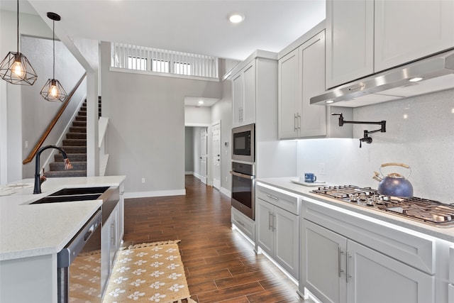 kitchen with stainless steel appliances, pendant lighting, decorative backsplash, sink, and dark wood-type flooring