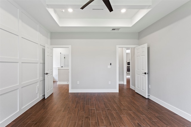 unfurnished bedroom with a raised ceiling, ceiling fan, and dark hardwood / wood-style floors