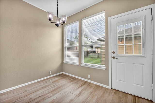 unfurnished dining area with a notable chandelier and light hardwood / wood-style flooring