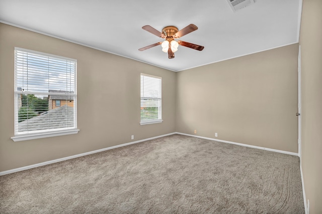 carpeted spare room featuring ceiling fan, visible vents, and baseboards