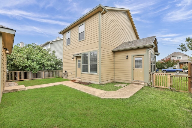 back of house featuring a lawn and fence