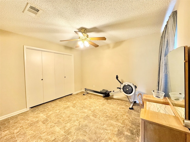 workout area with a textured ceiling and ceiling fan