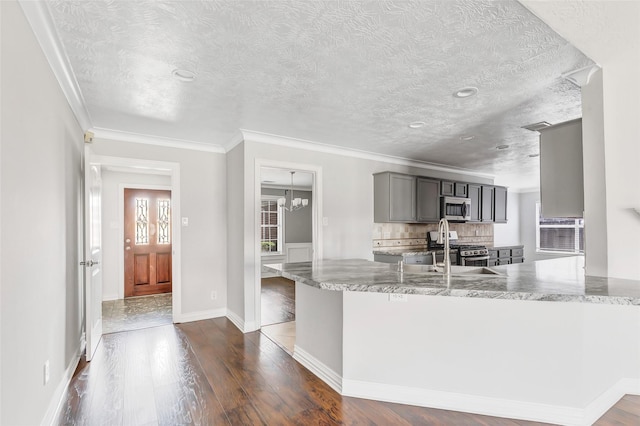 kitchen featuring gray cabinetry, light stone counters, kitchen peninsula, stainless steel appliances, and dark wood-type flooring