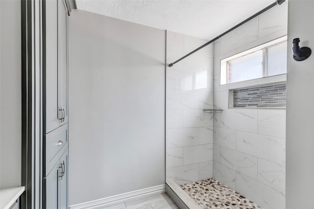 bathroom featuring a textured ceiling and tiled shower