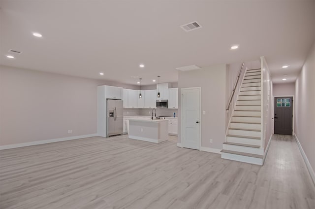 unfurnished living room with sink and light hardwood / wood-style floors