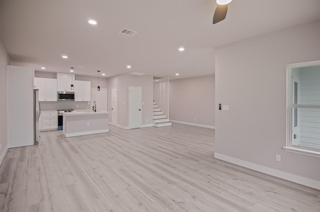 unfurnished living room featuring ceiling fan, light hardwood / wood-style flooring, and sink