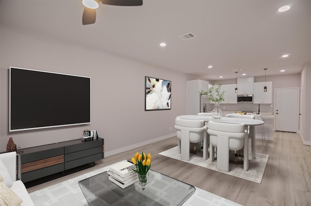 living room with light wood-type flooring and ceiling fan