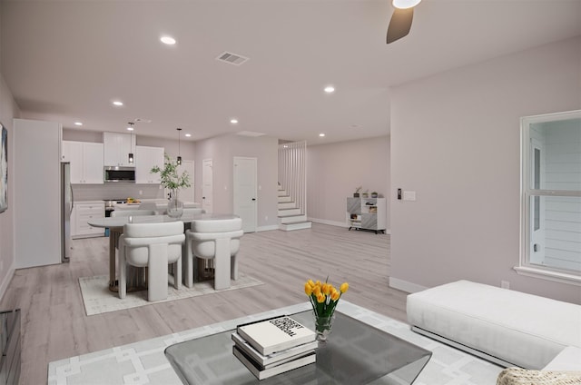 living room with ceiling fan and light hardwood / wood-style flooring