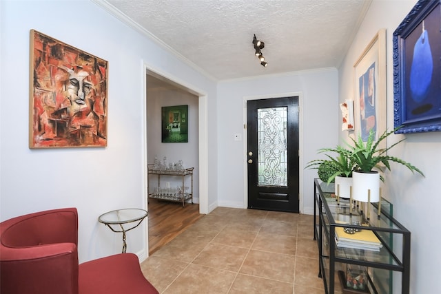 foyer entrance featuring ornamental molding, light tile patterned flooring, and a textured ceiling