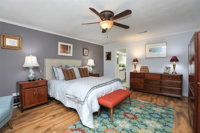 bedroom with crown molding, hardwood / wood-style floors, ensuite bath, and ceiling fan