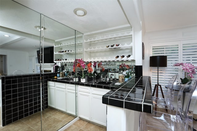 bar with tile countertops, white cabinets, and light tile patterned floors